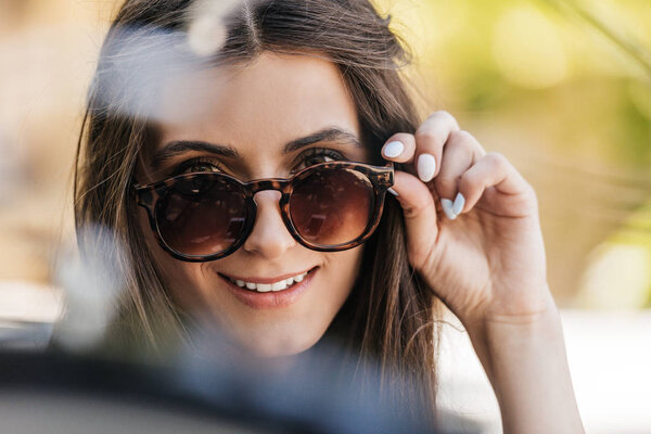 portrait of of beautiful young woman in sunglasses on street