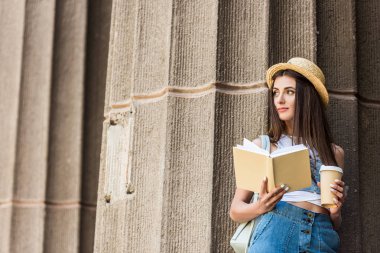 Genç ve güzel kadın sokağa dön açık kitap ve kahve ile portresi