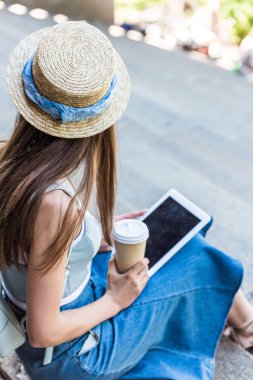 kadının sokakta basamaklarda oturup gitmek için tablet ve kahve ile kısmi görünümü