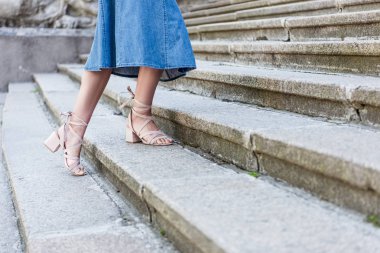 Kırpılan atış kadının sokakta basamaklarda ayakta kot etek ve şık ayakkabı