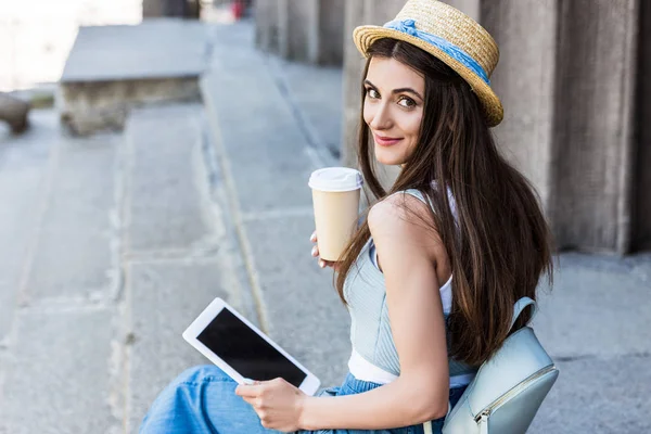 年轻的微笑的妇女与片剂和咖啡的侧面坐在台阶上 — 图库照片