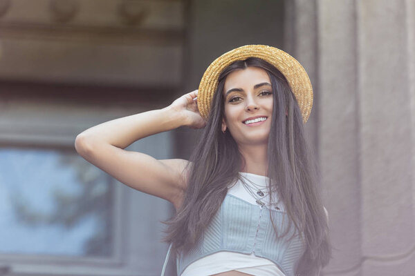 portrait of beautiful smiling woman in straw hat on street