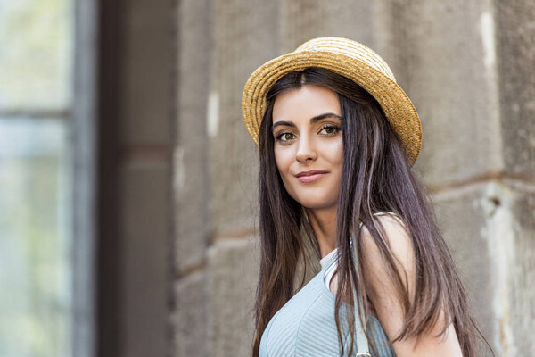portrait of young beautiful woman in straw hat on street