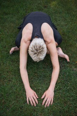 Genişletilmiş çocuk kadın pratik yoga Park çimenlerin üzerinde (Utthita Balasana) teşkil