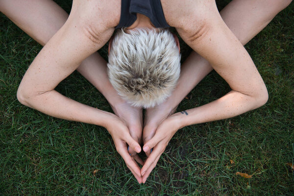 top view of woman practicing yoga on grass in park