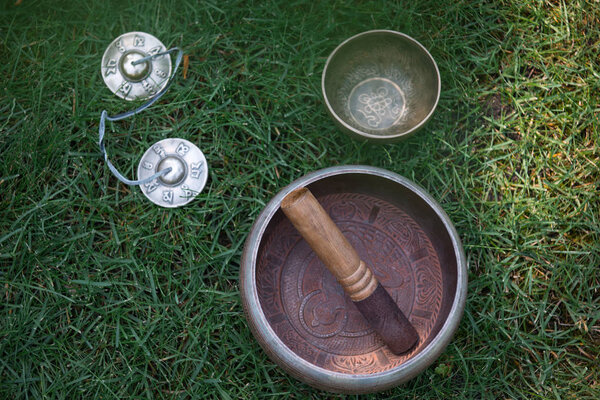 top view of tibetan singing bowls on green grass in park