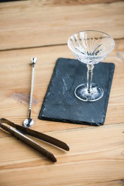 close-up view of margarita glass on slate board and tongs on wooden table clipart