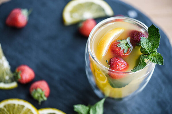 close-up view of refreshing summer cocktail with strawberries and mint on slate board
