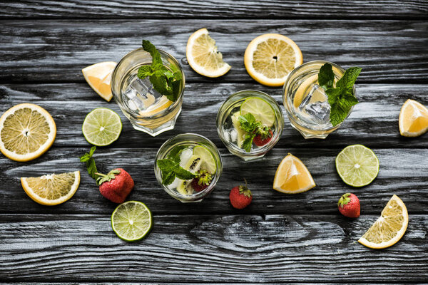 top view of cold summer cocktails in glasses and ingredients on wooden table