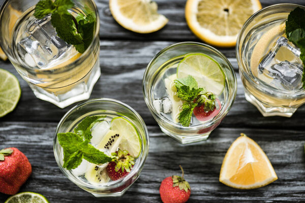 top view of glasses with delicious strawberry kiwi mojito cocktail on wooden table 