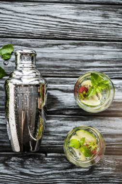 ahşap masa üzerinde shaker ve çilek kivi mojito bardaklarda üstten görünüm
