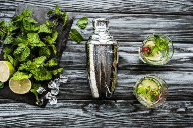 ahşap masa üzerinde shaker, gözlük ve çilek kivi mojito için malzemeler üstten görünüm