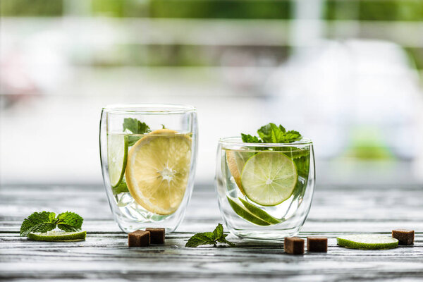 close-up view of two glasses with fresh cold mojito on table  