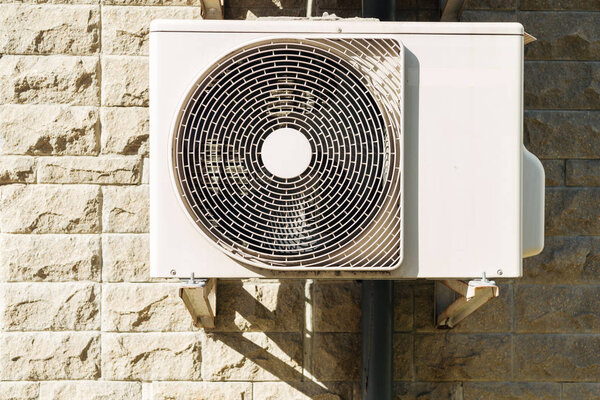 white air conditioner hanging on wall at sunny day