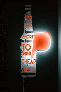 illuminated beer bottle symbol on dark wall in pub with 