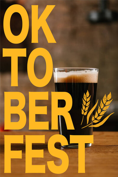 Крупный план стекла с вкусным темным пивом на столе в пабе с надписью "Октоберфест"
