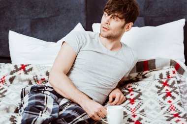 Genç adamın kahve fincanı evde yatakta döşeme seçici odak