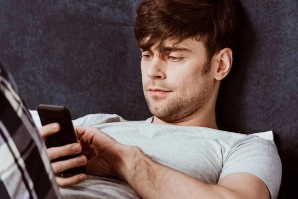 Retrato Hombre Guapo Usando Teléfono Inteligente Mientras Está Acostado Cama — Foto de Stock