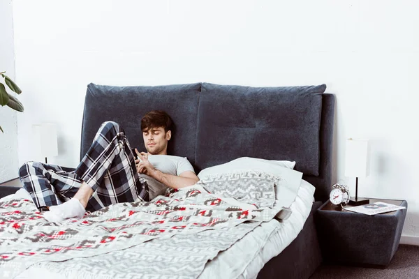 Jeune Homme Beau Utilisant Smartphone Tout Étant Couché Dans Lit — Photo