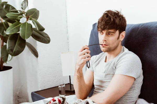 Pensive Man Holding Eyeglasses While Sitting Bed Home — Stock Photo, Image