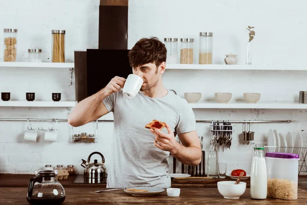 Young Man Drinking Coffee Eating Toast Jam Breakfast Kitchen — Stock Photo, Image