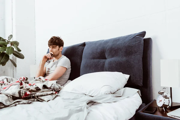 Düşünceli Erkek Yatakta Evde Otururken Gözlük Tutan — Ücretsiz Stok Fotoğraf