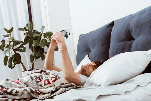 Genç Adam Çalar Saat Yatakta Evde Devre Dışı Bırakarak Yan — Stok fotoğraf
