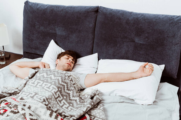 selective focus of man stretching in bed during morning time at home