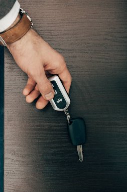 cropped image of businessman taking off remote car key from table  clipart