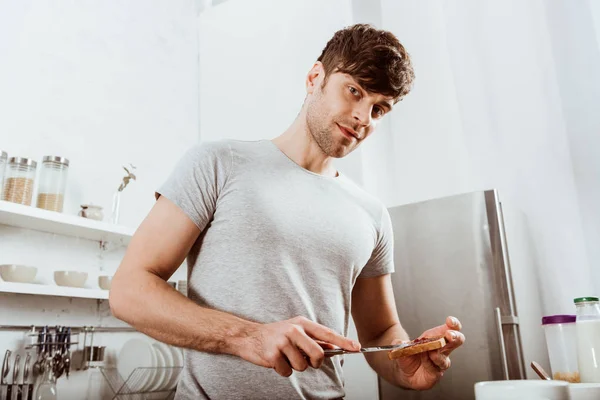 Low Angle View Man Looking Camera Spreading Toast Jam Kitchen — Stock Photo, Image