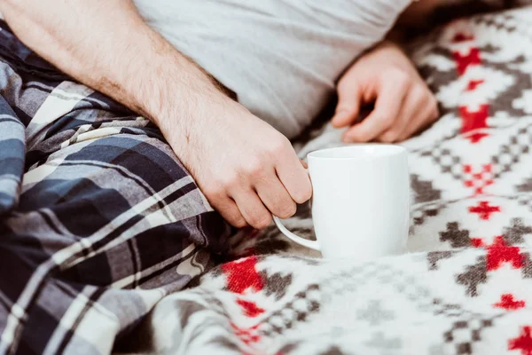 自宅のコーヒー カップが付いているベッドに坐っていた男の画像をトリミング  — 無料ストックフォト