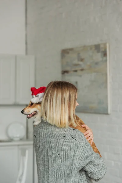 Ung Kvinna Som Bär Söt Corgi Hund Santa Hatt Hemma — Gratis stockfoto