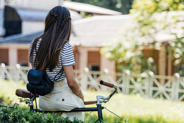 Back view of woman with back pack leaning on retro bicycle in park — Stock Photo