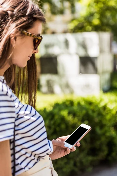 Vue latérale de jeune femme attrayante en utilisant un smartphone sur la rue — Photo de stock