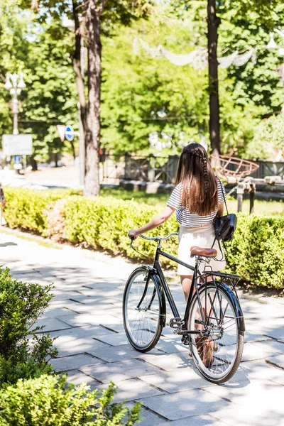 Back view of woman with retro bicycle walking on street — Stock Photo