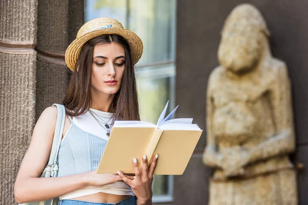 Portrait of student in straw hat reading book on street — Stock Photo