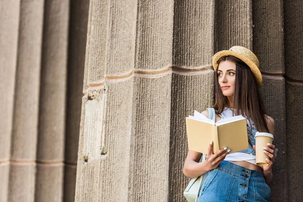 Портрет красивой молодой женщины с открытой книгой и кофе, чтобы выйти на улицу — стоковое фото