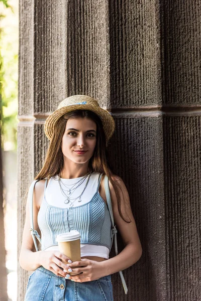 Портрет молодой улыбающейся женщины с кофе в руках на улице — стоковое фото