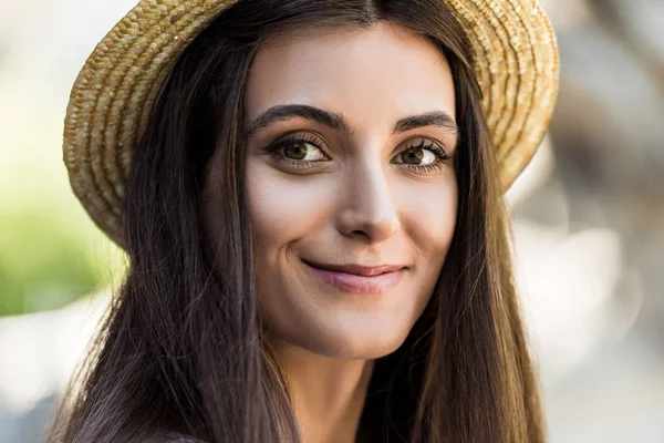 Portrait of beautiful smiling woman with long hair in straw hat on street — Stock Photo