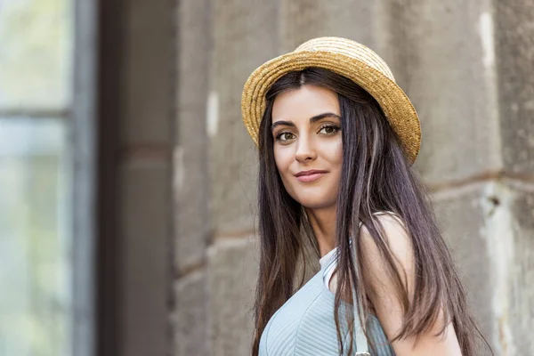 Portrait of young beautiful woman in straw hat on street — Stock Photo