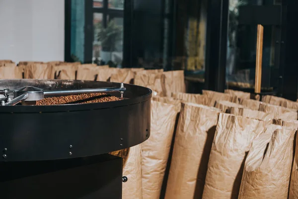 Industrieller Kaffeeröster mit großen Papiertüten gefüllt mit Kaffeebohnen — Stockfoto