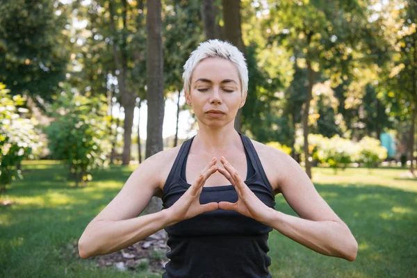 Woman meditating with closed eyes in park — Stock Photo