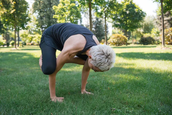 Женщина практикует йогу и делает позирование на руках на траве в парке — стоковое фото