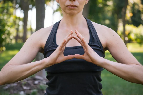 Cropped image of woman meditating and making gesture with hands in park — Stock Photo