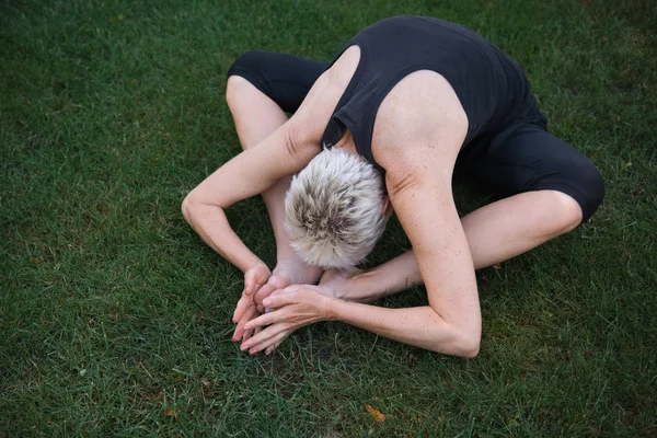 Vista de ángulo alto de la mujer que practica yoga sobre hierba en el parque - foto de stock