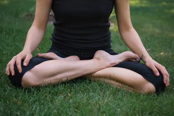 Обрезанный образ женщины, практикующей йогу в позе лотоса на траве в парке — стоковое фото