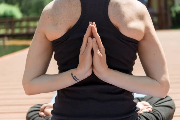 Cropped image of woman practicing yoga in lotus pose and hands in namaste gesture in park — Stock Photo