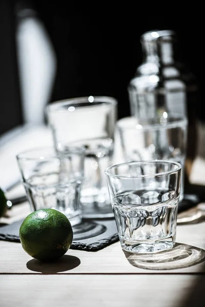 Vue rapprochée du citron vert frais et des verres vides avec agitateur, mise au point sélective — Photo de stock