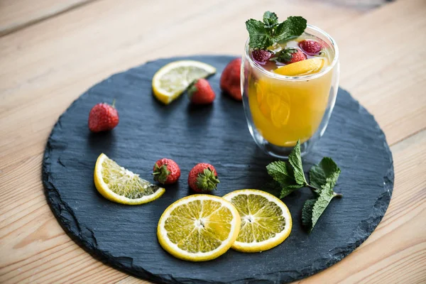 Fruity summer cocktail with strawberries and mint in glass on slate board — Stock Photo