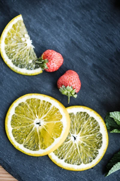 Вид сверху на свежий нарезанный лимон и спелую клубнику на доске — стоковое фото
